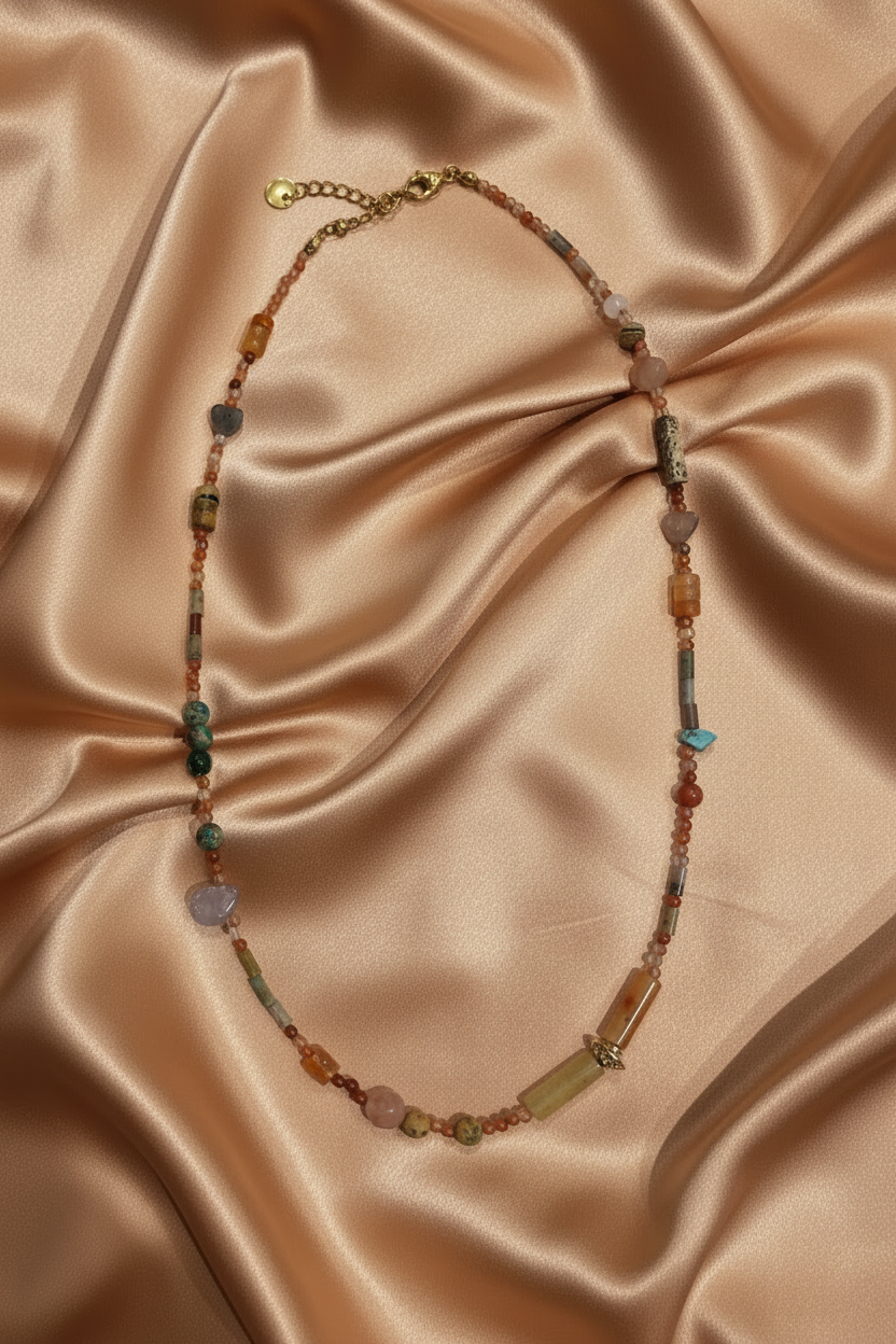 Mixed gemstone necklace flat lay on blush champagne satin